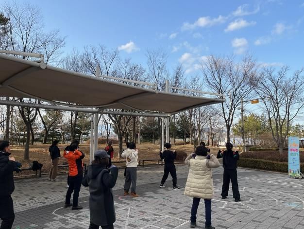 화성특례시 병점구보건소가 운영하는 비만 예방 프로그램 ‘온가족 공원체조’에 참여한 시민들이 공원에서 체조를 하고 있다